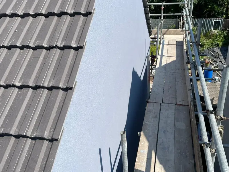 Freshly rendered white gable wall beside a tiled roof