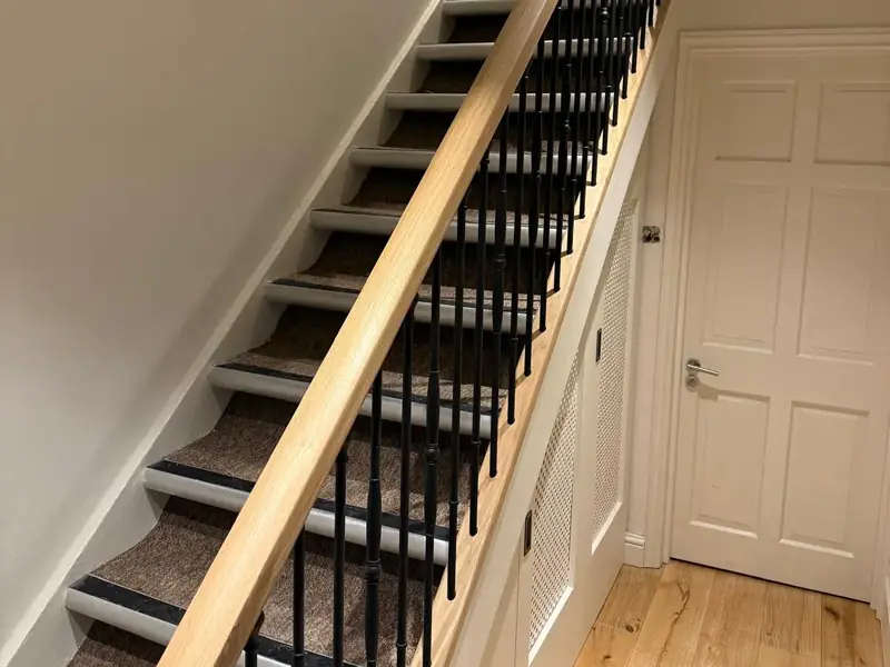 Refurbished staircase with an oak handrail and black iron spindles