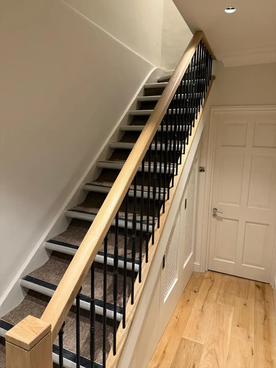 Staircase with an oak handrail and newel post and black iron spindles