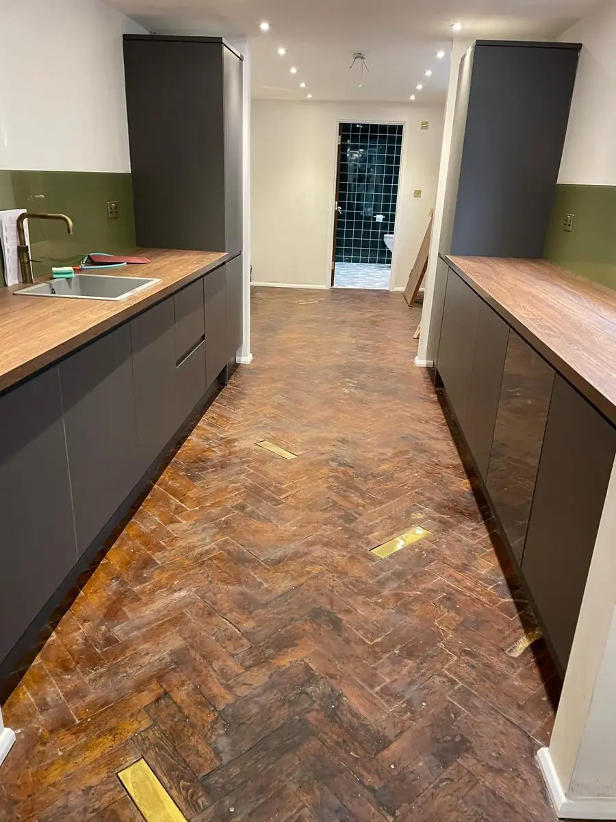 Galley kitchen with dark grey units and wood worktops