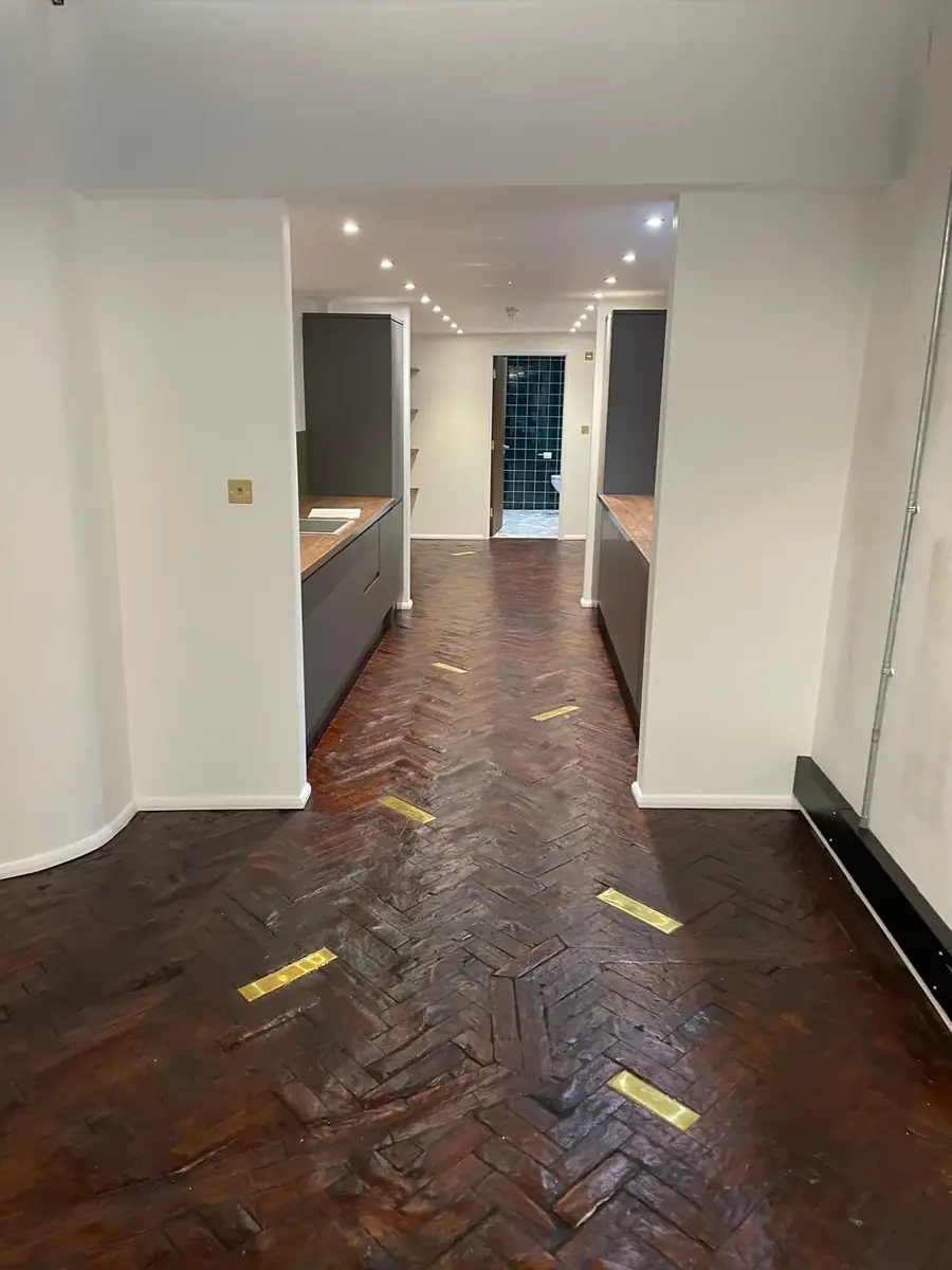 Galley kitchen and hallway with herringbone parquet and brass floor sockets