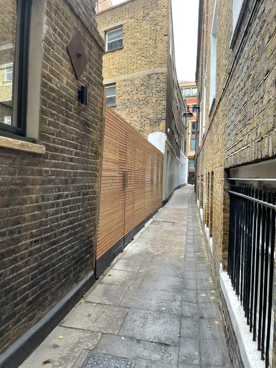 Slatted timber screen along a brick-walled side alley