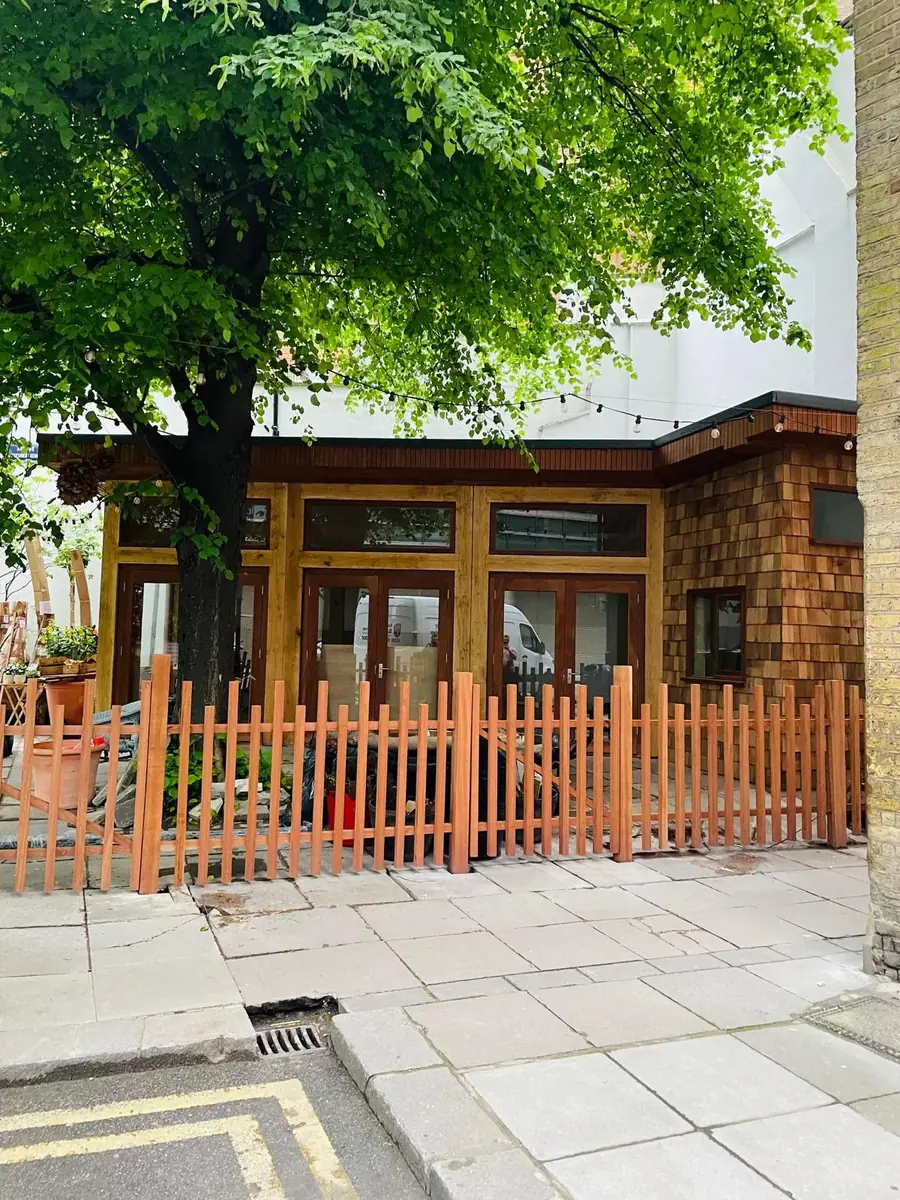 Natural timber picket fence in front of a garden building
